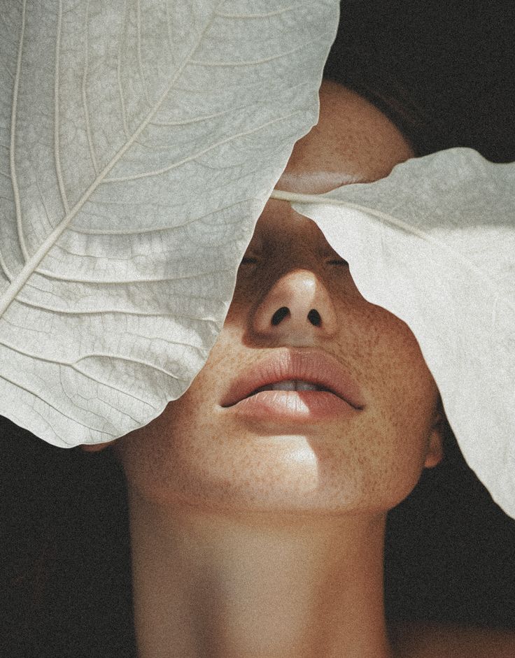 Skincare lifestyle portrait framed by pale leaves, evoking a moment of pampering and the quiet luxury of beauty bundles.