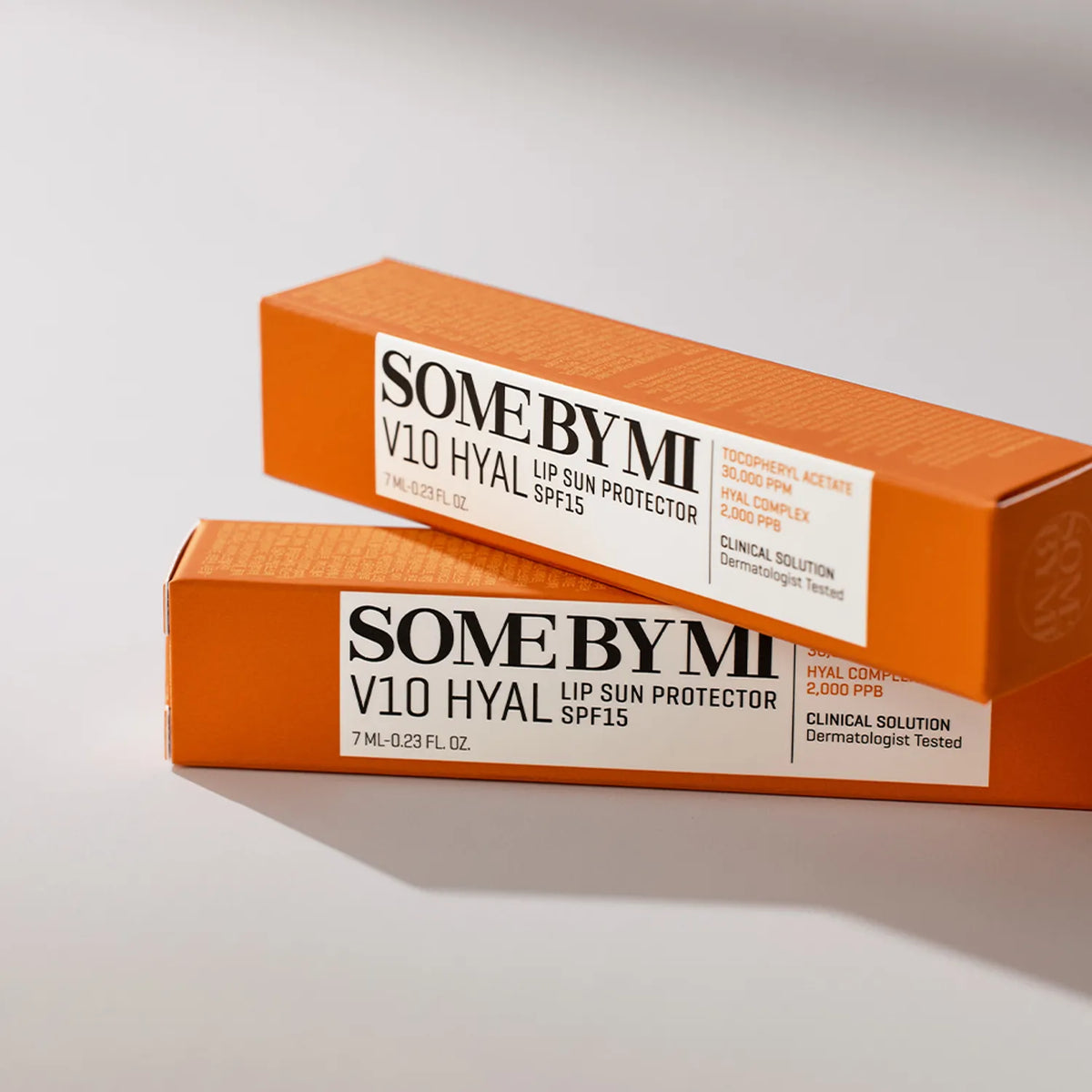 Two boxes of SOME BY MI V10 Hyal lip sun protector on a light gray background