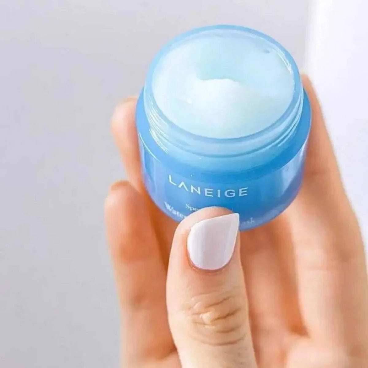 Hand holding an open LANEIGE Water Sleeping Mask mini jar